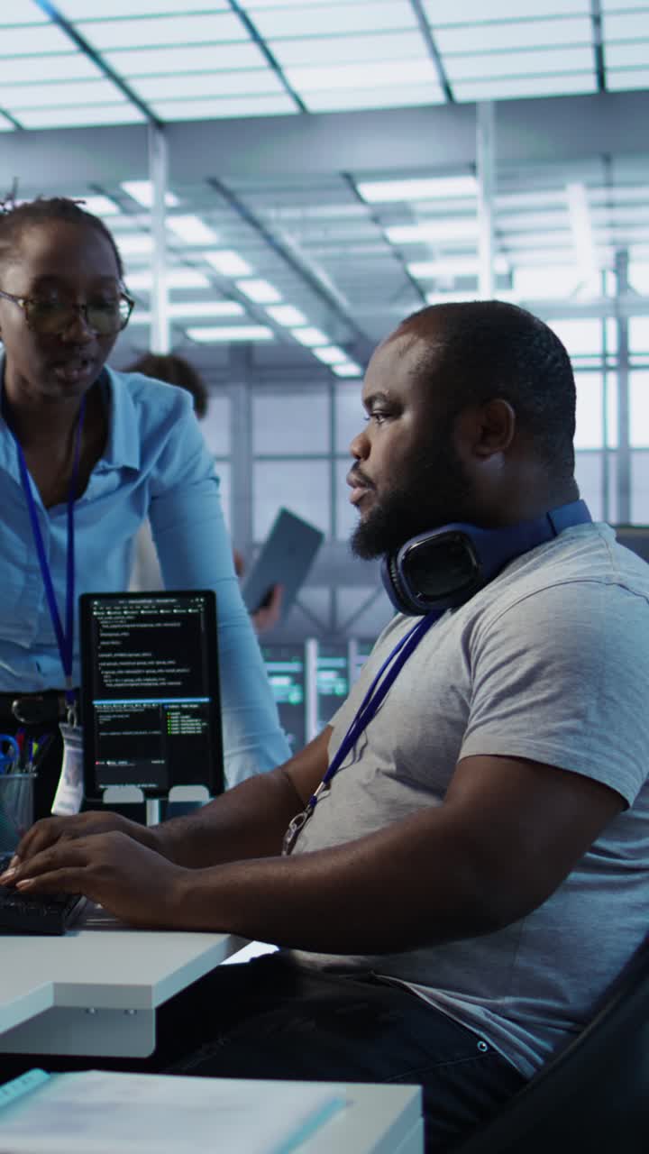 Vertical video Team of technicians using PC to check for system failures in data center