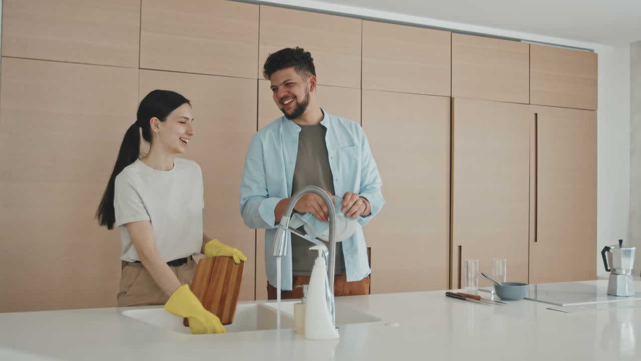 Smiling Young Couple Washing Dishes Together