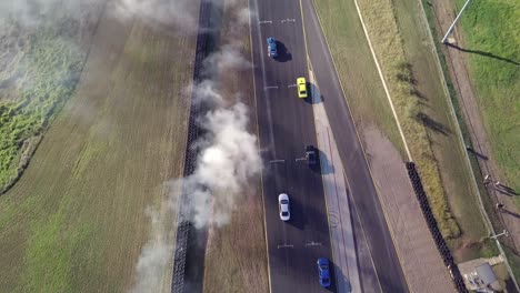 bird's eye view of cars drifting battle on asphalt race track with smoke from burning tires at sydney motorsport park in australia - aerial shot