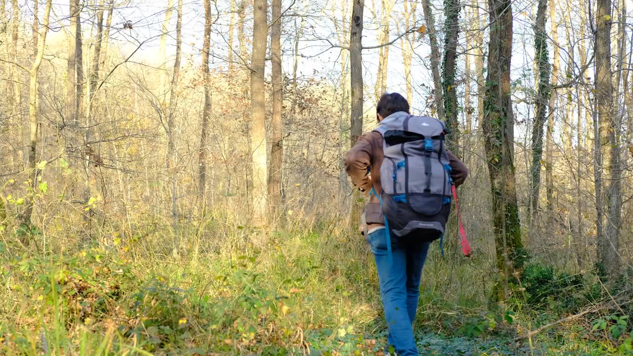 hombre de mochila caminando por el bosque