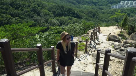 joven caucásica con mochila trepando por el sendero gwanaksan con valla en un día soleado de verano en seúl, corea del sur