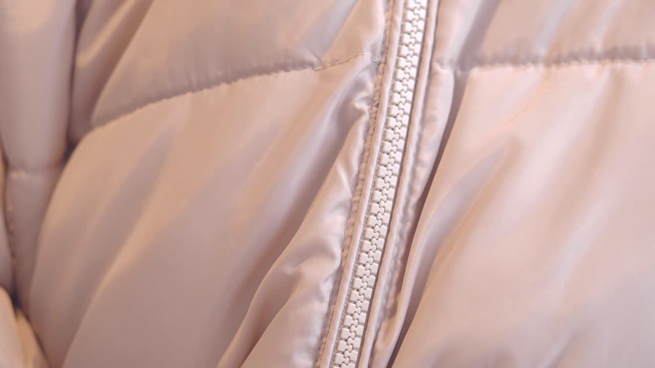 Close-up of a light pink quilted jacket with zipper