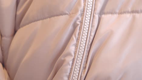 close-up of a light pink quilted jacket with zipper