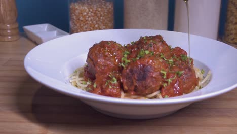 rociar aceite de oliva sobre albóndigas caseras frescas en un plato de pasta