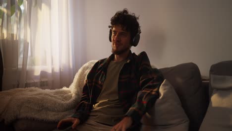 hombre relajándose en casa con auriculares y teléfono inteligente