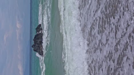 Vertical-Shot-of-Banbanon-Beach-in-Slow-Motion-with-Waves-Rolling-Over-Sandy-Shoreline