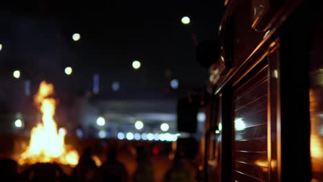 119 firetruck with emergency flashing lights next to burning fire, blurred firemens standing by the vehicle at night in seoul city, south korea