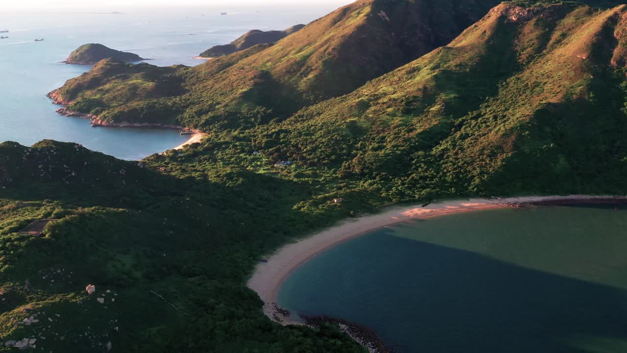 Aerial view of beautiful mountains surrounded by water. Drone view of coastline divided by mountains slope in Lantau Island, Hong Kong.