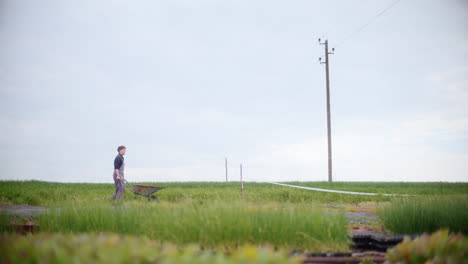 Farmer-With-Wheelbarrow-Walking-In-Field