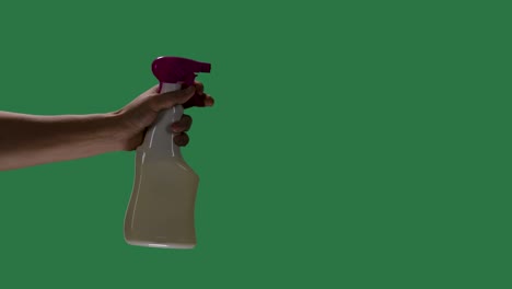 silhouette of a mans hand in blue protective gloves holds a spray bottle and sprays a disinfectant alcohol agent to disinfect the covid 2019 corona virus. green screen, chroma key. slow motion. close up