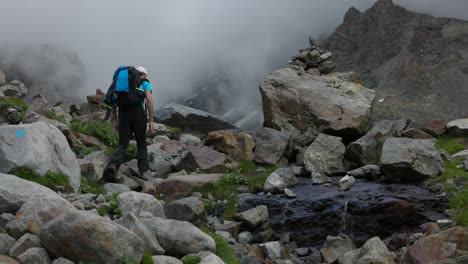 joven excursionista caucásico camina a través del campo de rocas en los alpes italianos en la niebla