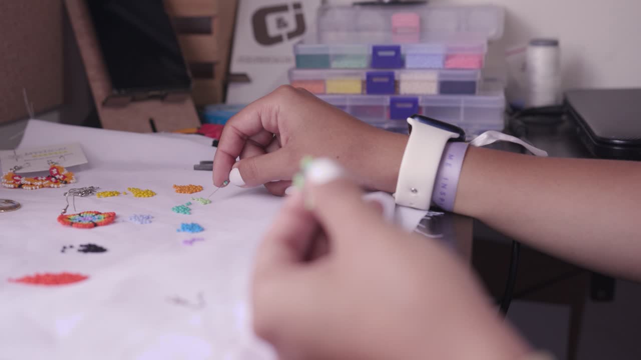 Closeup of woman&acute;s hands threading beads on a needle