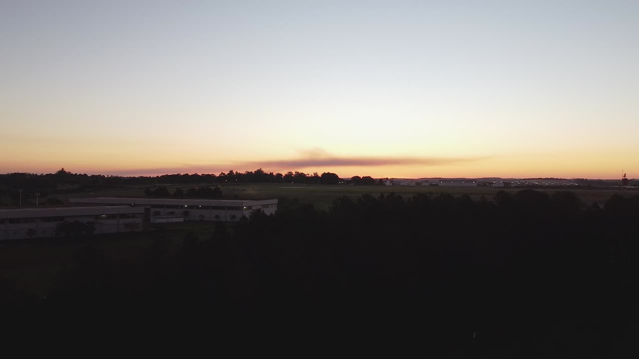 Drone clip of a large building surrounded by thick forest, at sunset