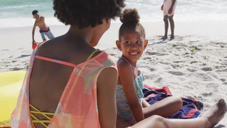 familia afroamericana sonriente usando crema solar en una playa soleada