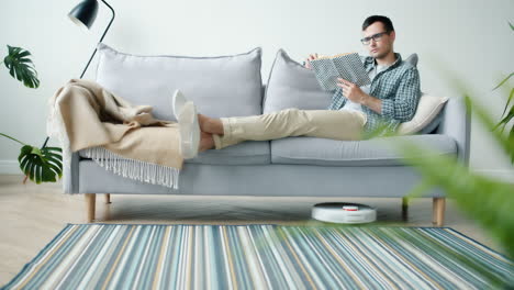 man relaxing on couch reading a book