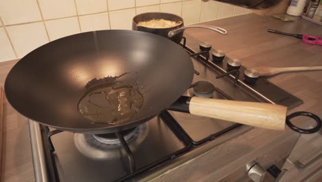 pouring olive oil in an iron wok over burner stove