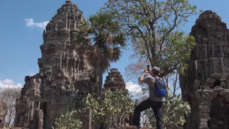 Mittlere-Außenaufnahme-Eines-Touristen,-Der-Mit-Seinem-Telefon-In-Angkor-Wat-Eine-Antike-Tempelstruktur-Fotografiert
