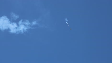 skydivers descend through clear blue sky