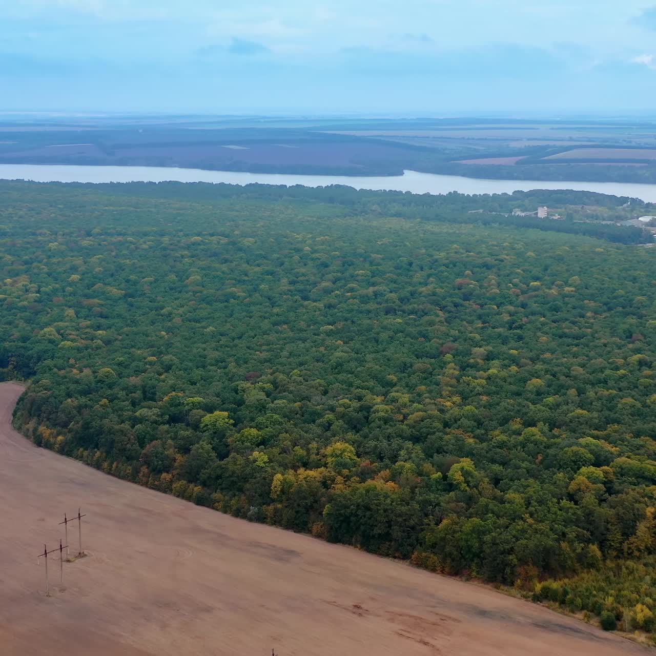 Beautiful landscape. Amazing view of nature. Background of green forest, river and fields. High-voltage electric towers on field. Aerial view