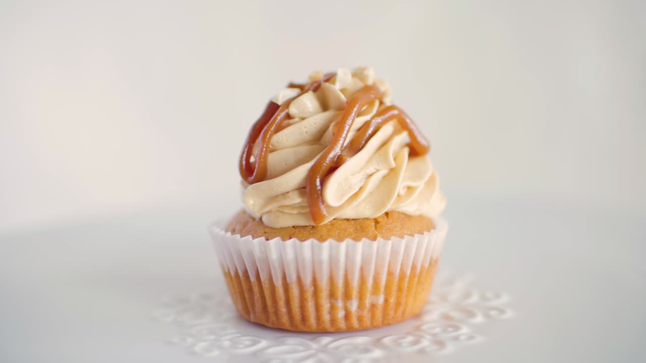 흰색 장식 접시, 앞면에서 천천히 회전하는 땅콩 맛 컵케이크 1개
