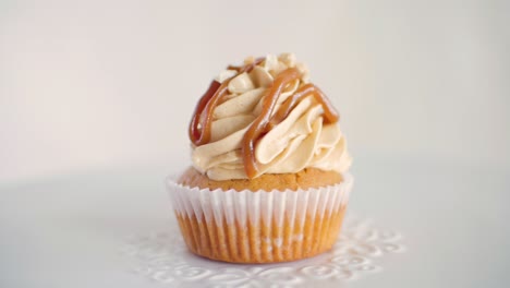 one peanut flavor cupcake rotating slowly on white decorated plate, front