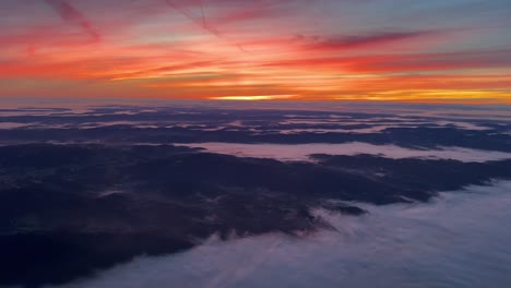 unique pilot point of view from a jet cockpit flying southward over germany at dawn with an intense orange sky and foggy landscape