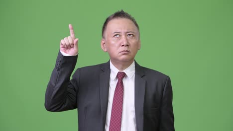 mature japanese businessman thinking while pointing finger up