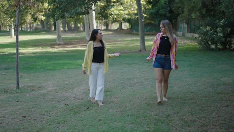 two women walking and talking in a park