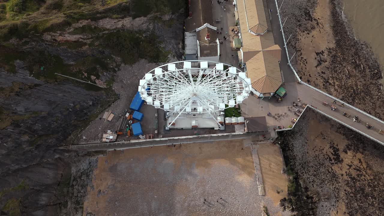 Aerial top down shot of famous The Big Wheel situated at Mumbles Pier Swansea during daytime in England.