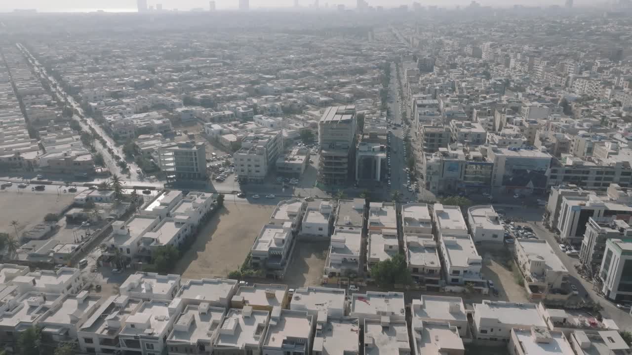 Aerial drone bird's eye view over traffic movement on both sides of residential buildings in Karachi, Pakistan on a sunny day