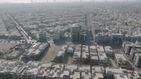 Aerial-drone-bird's-eye-view-over-traffic-movement-on-both-sides-of-residential-buildings-in-Karachi,-Pakistan-on-a-sunny-day