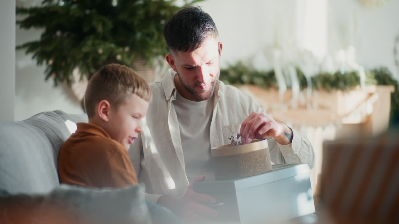 아빠는 작은 아들에게 크리스마스 장식품을 보여줍니다.