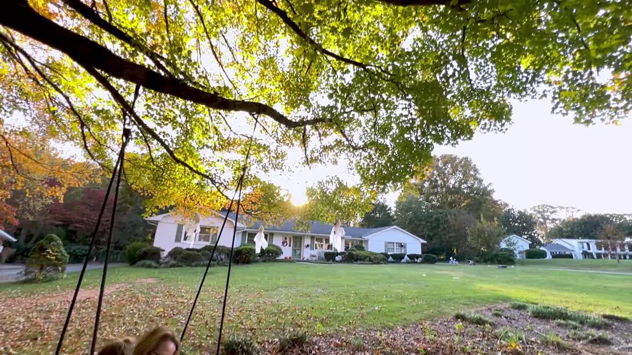 grandmother swings with kids under tree with fall leaves