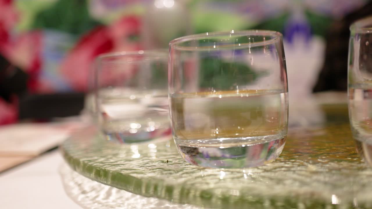 Two glasses of water on a rotating glass table with colorful background and soft lighting
