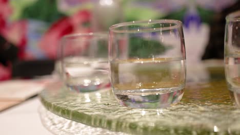 two glasses of water on a rotating glass table with colorful background and soft lighting