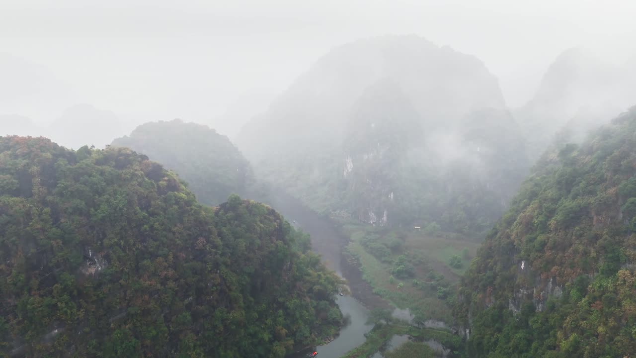 Misty limestone mountains rise over lush valleys and a winding river in Trang An, Ninh Binh, Vietnam