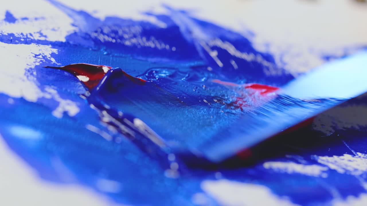 la pintura acrílica roja y azul se mezcla con una espátula