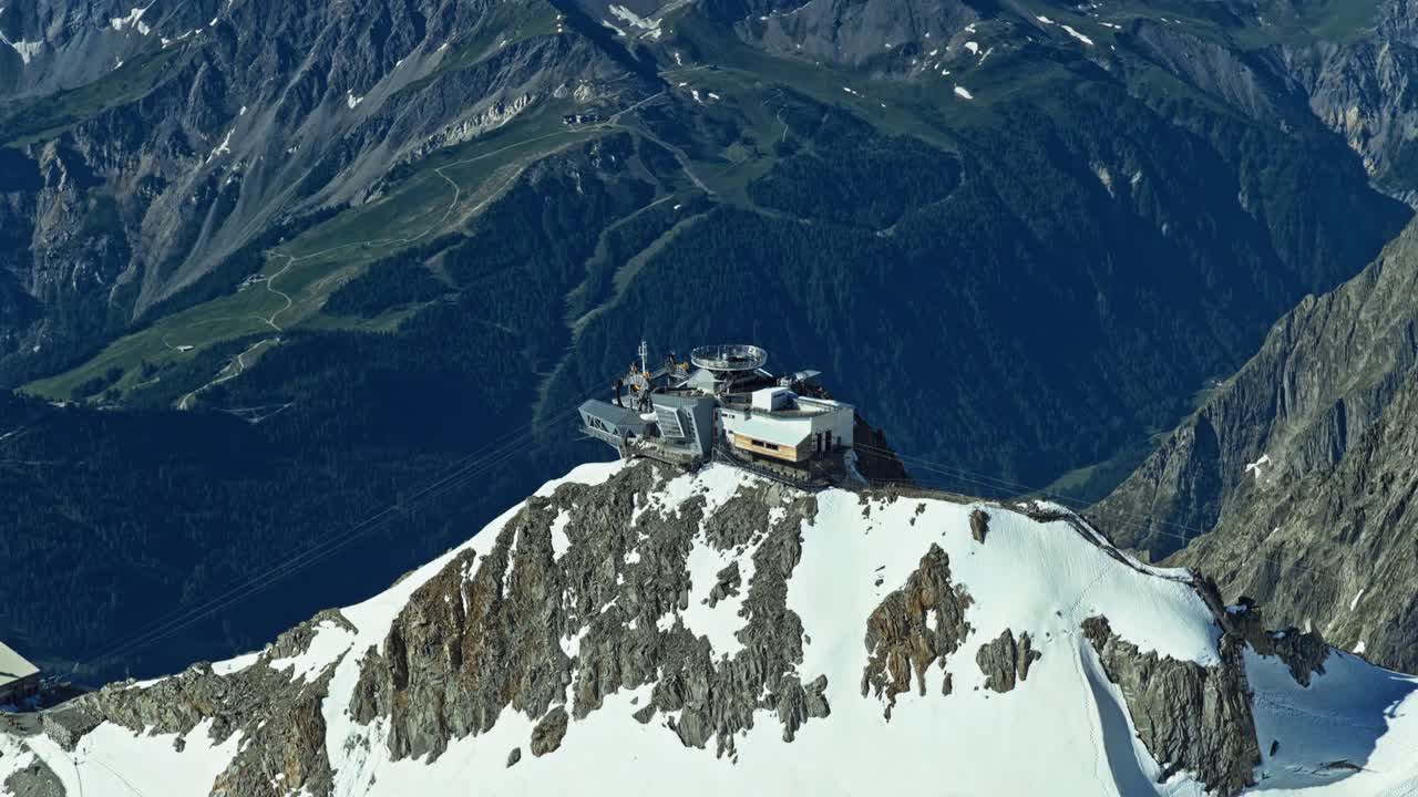 Tòa nhà ga đỉnh núi nằm trên đỉnh Aiguille du Midi thuộc dãy núi Alps của Pháp gần Chamonix, nổi bật trên nền bầu trời xanh trong rộng lớn và những đỉnh núi tuyết cao hiểm trở.