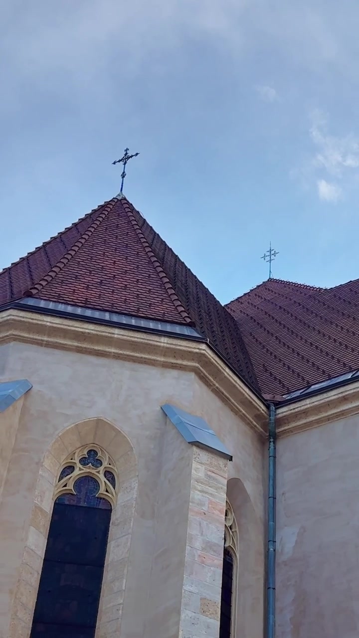 Exterior da Igreja de São Cantiano com janelas góticas e telhado de telhas em Kranj, Eslovênia, pedra limpa e ornamentada
