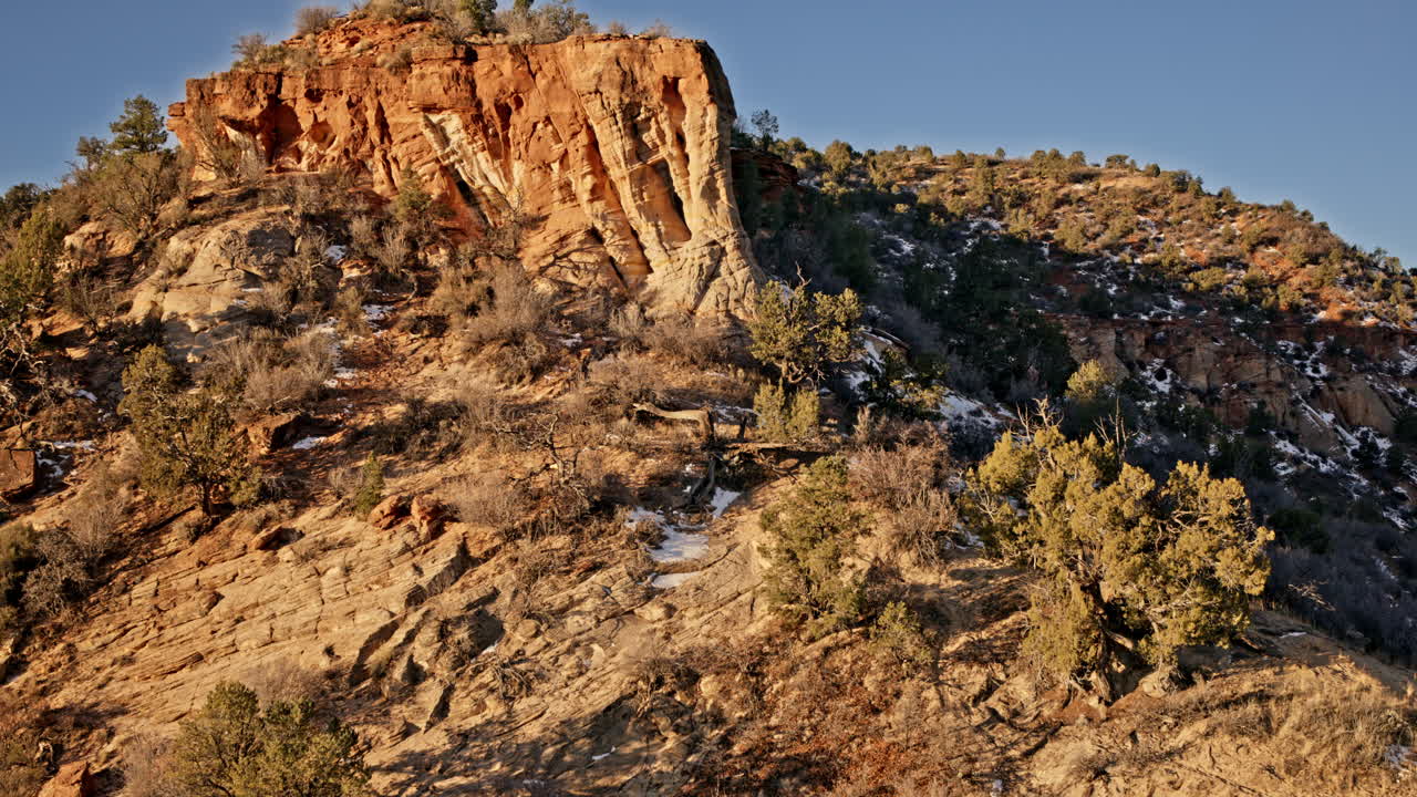 Drone footage sweeping over a red rock landscape, focusing on a stunning natural arch at sunrise.