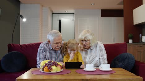 grandparents and granddaughter watching tablet together