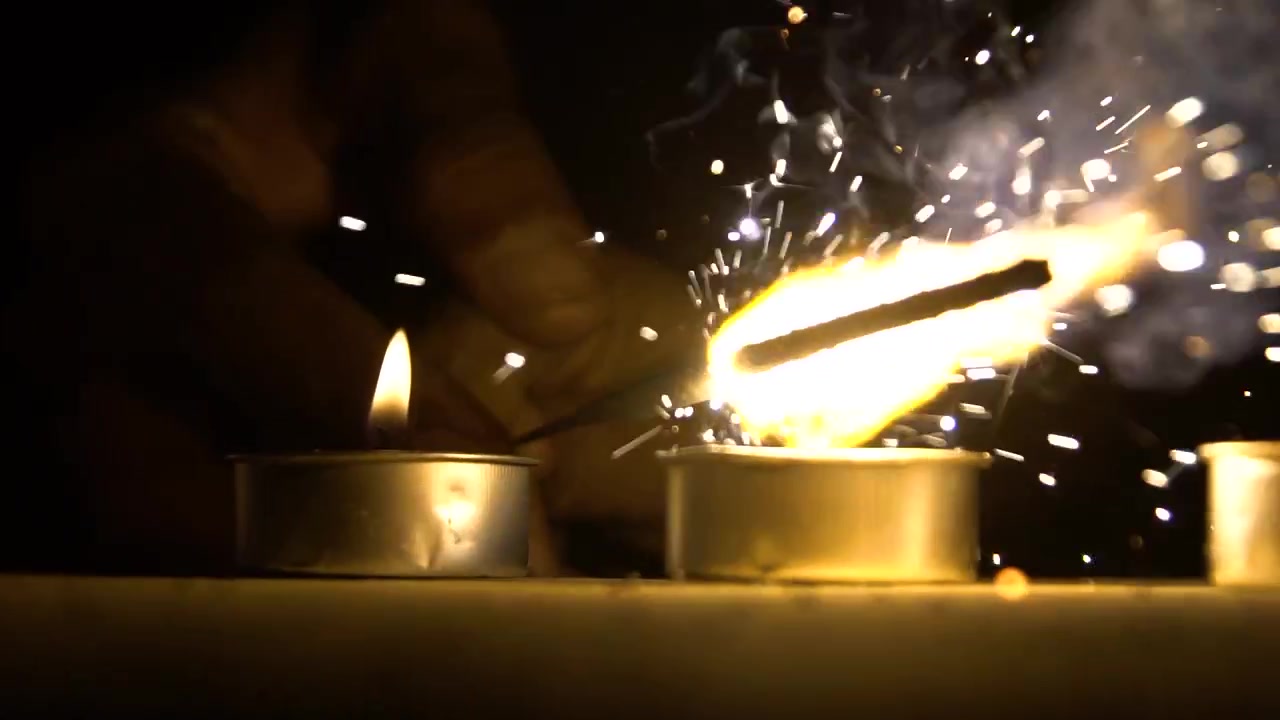 Zbliżenie dłoni zapalającej świece zimnym ogniem, świętującej Nowy Rok lub Diwali nocą.