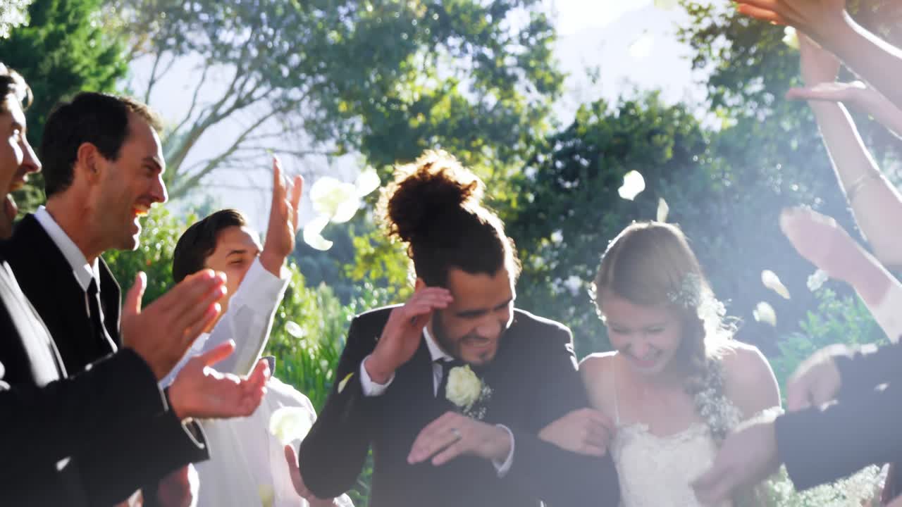 신랑과 신부는 손님들이 꽃잎을 던지는 동안  ⁇ 고 있습니다.