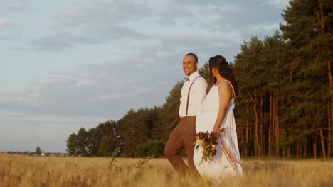 pareja caminando en un campo de trigo al atardecer