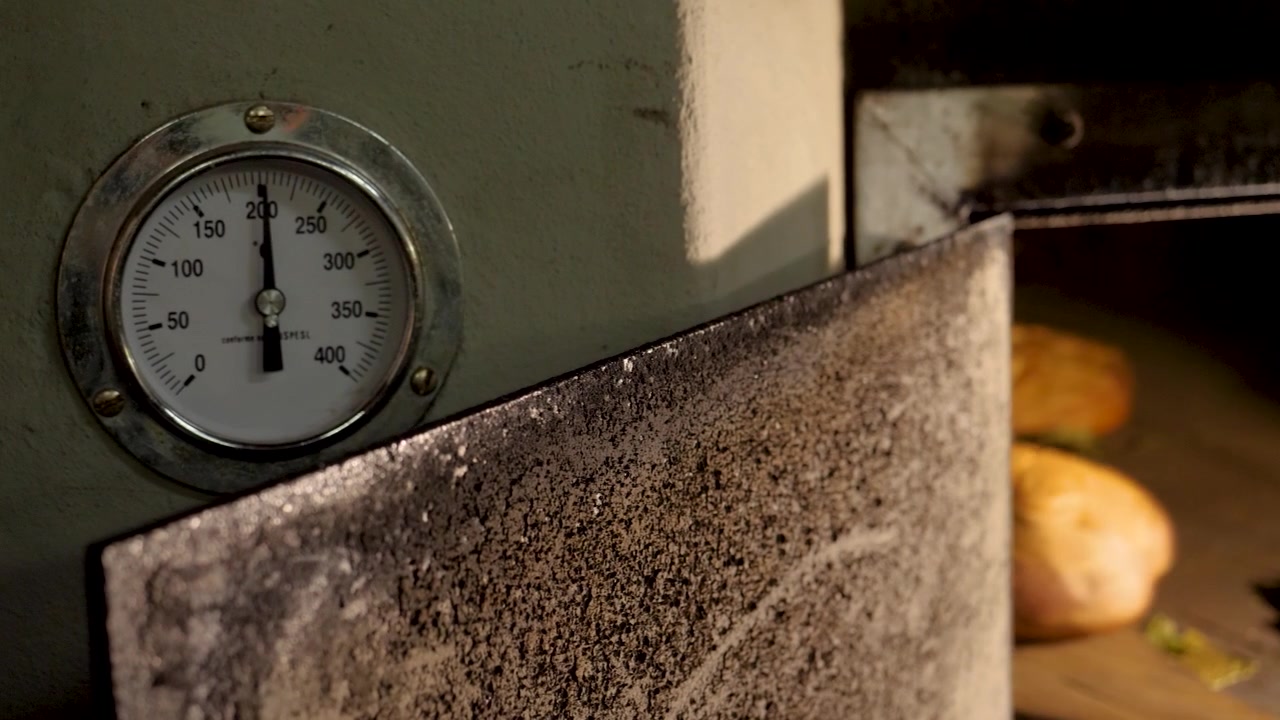 Forno industriale tradizionale a legna che cuoce il pane, termometro analogico