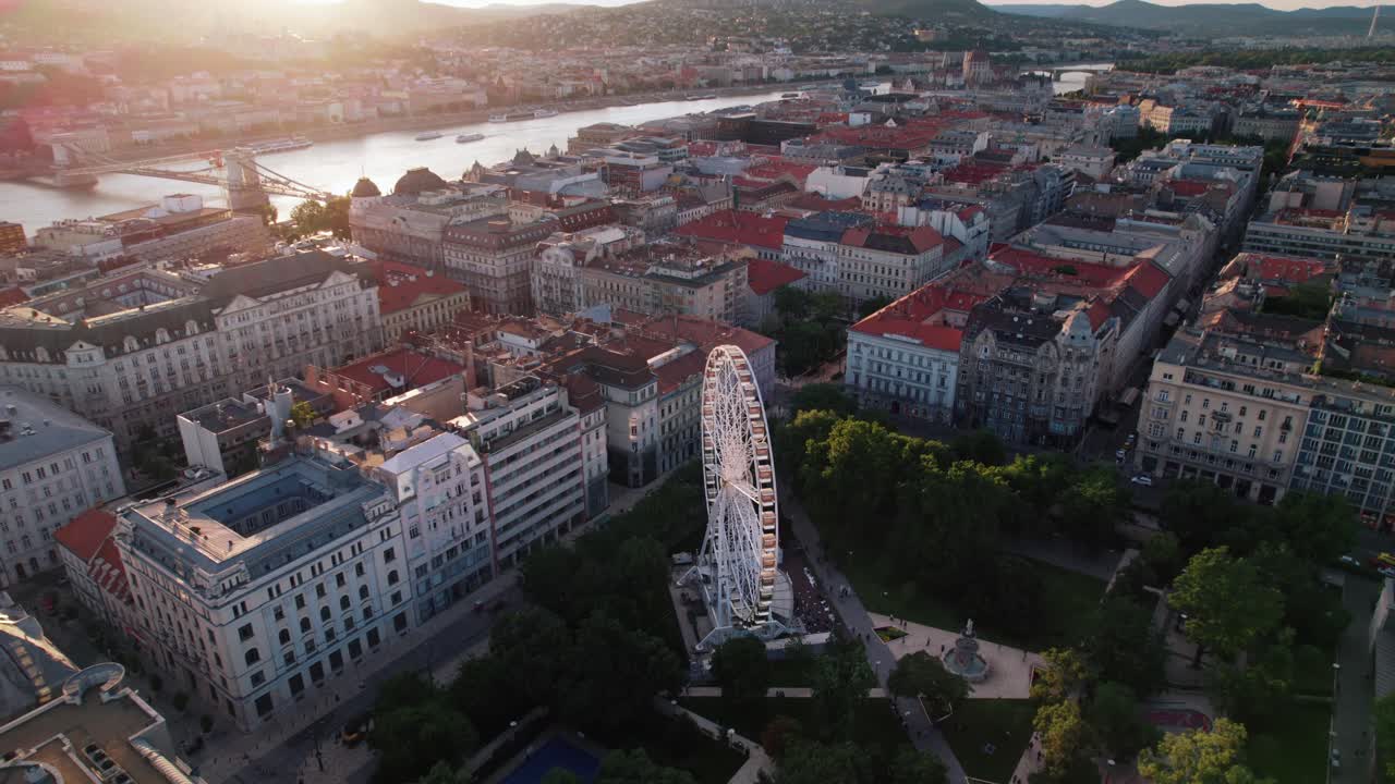 Budapest con la ruota panoramica, edifici e un fiume al tramonto, vista aerea.