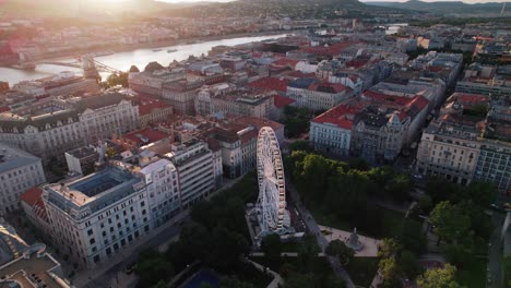 budapest featuring the ferris wheel, buildings, and a river at sunset, aerial view