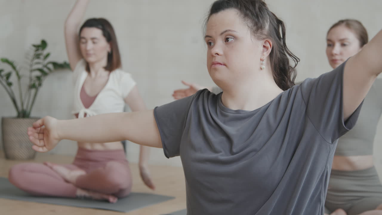 Young Woman With Down Syndrome Stretching During Group Yoga Class