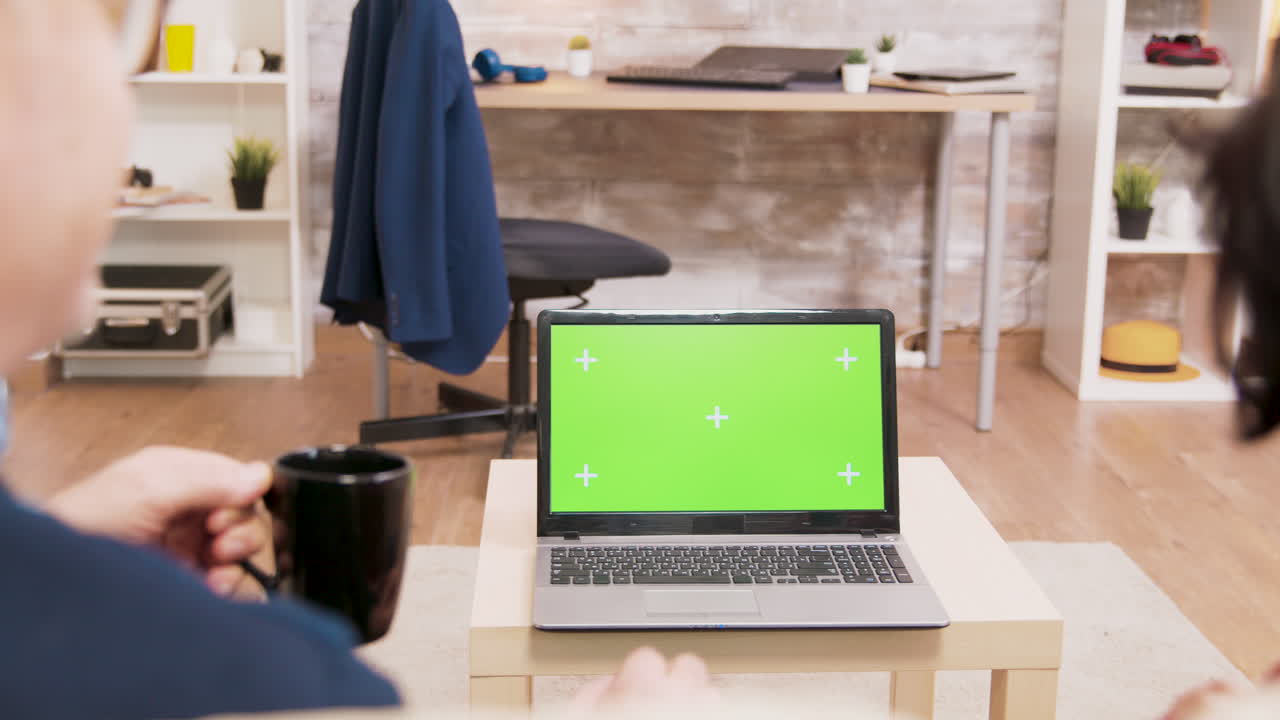 People looking at laptop with green screen