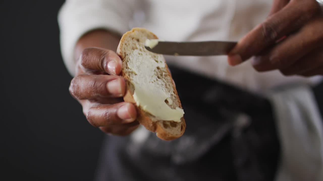Video of cook grease bread with butter on black background